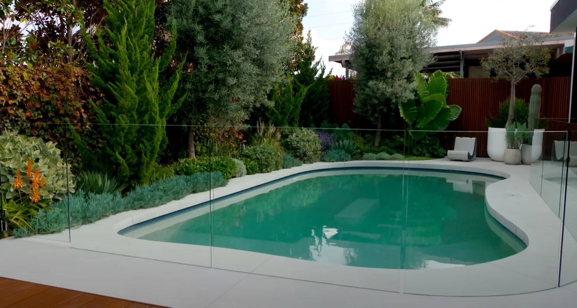 Modern pool area with professional landscape lighting and lush plantings